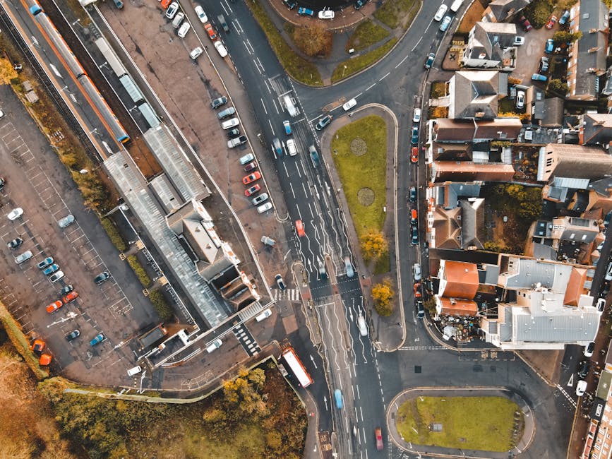 Drone view of a busy urban intersection surrounded by residential and commercial buildings.